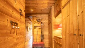 Ein Holzraum mit Skiregal, Sitzbank und Kamin.