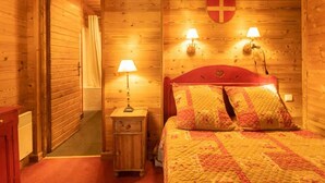 Ein Zimmer mit Holzboden, einem Bett, zwei Wandlampen, einem Kleiderständer und einem an der Wand hängenden Mantel.