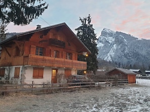 A wooden chalet with a balcony, surrounded by a wooden fence, and a mountain backdrop. - Quiet apartment, near center, pets allowed (Samoëns)