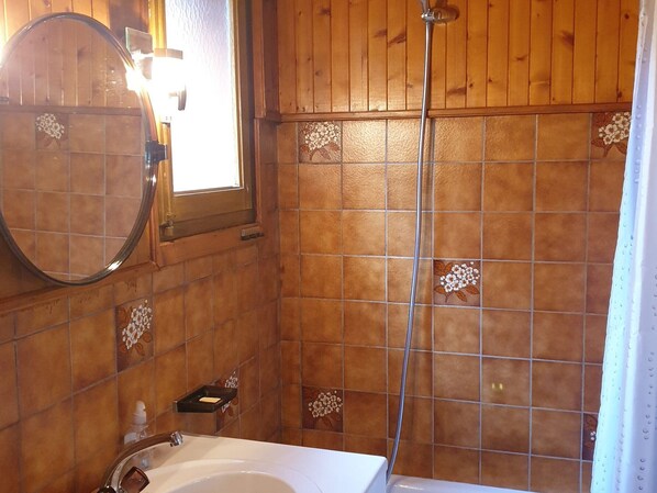 A bathroom with wooden walls, a round mirror, a shower, and a sink with a soap dispenser. - Quiet apartment, near center, pets allowed (Samoëns)