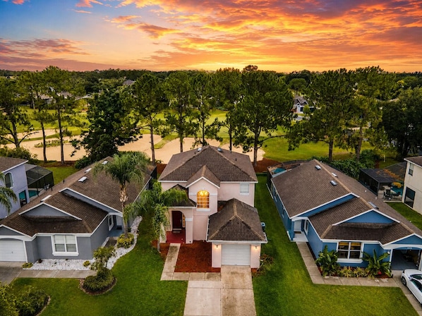 A residential area with houses, a driveway, and a golf course in the background.