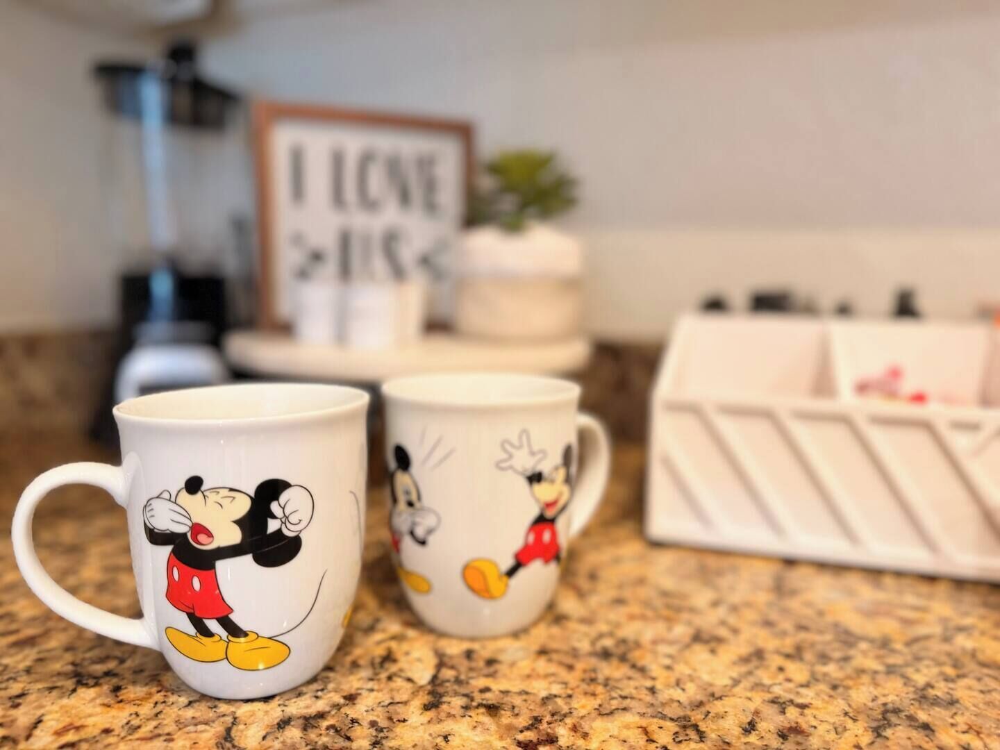 Two mugs with cartoon characters on a kitchen counter.