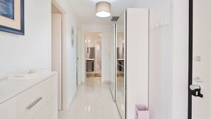 A hallway with a mirror, a door, and a light fixture. - GuestHost - Cozy 70 sqm apartment with terrace, able to accommodate up to 6 people, located on the 1st floor of a renovated villa (NO lift) 200 meters from the beach. The property boasts a shared garden and a private parking space. The accommodation, sur (Sanremo)