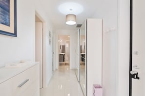 Un couloir avec un miroir, une porte et un luminaire.