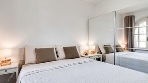 A hotel room with a large bed, bedside tables with lamps, a mirror, and a window with curtains. - GuestHost - Cozy 70 sqm apartment with terrace, able to accommodate up to 6 people, located on the 1st floor of a renovated villa (NO lift) 200 meters from the beach. The property boasts a shared garden and a private parking space. The accommodation, sur (Sanremo)