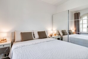 Une chambre d’hôtel avec un grand lit, des tables de chevet avec des lampes, un miroir et une fenêtre avec des rideaux.