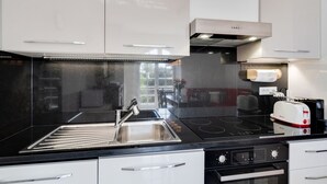 A modern kitchen with a stainless steel sink, black countertop, and a toaster. - GuestHost - Cozy 70 sqm apartment with terrace, able to accommodate up to 6 people, located on the 1st floor of a renovated villa (NO lift) 200 meters from the beach. The property boasts a shared garden and a private parking space. The accommodation, sur (Sanremo)