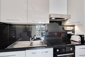 Eine moderne Küche mit Spüle aus Edelstahl, schwarzer Arbeitsplatte und einem Toaster.