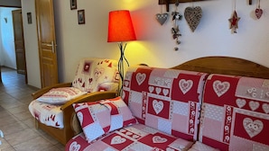 Un salon chaleureux avec un canapé à motifs rouges et blancs, une chaise en bois et un lampadaire rouge.