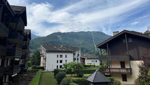 Un quartier résidentiel avec des immeubles à plusieurs étages, un jardin bien entretenu et une montagne en arrière-plan.