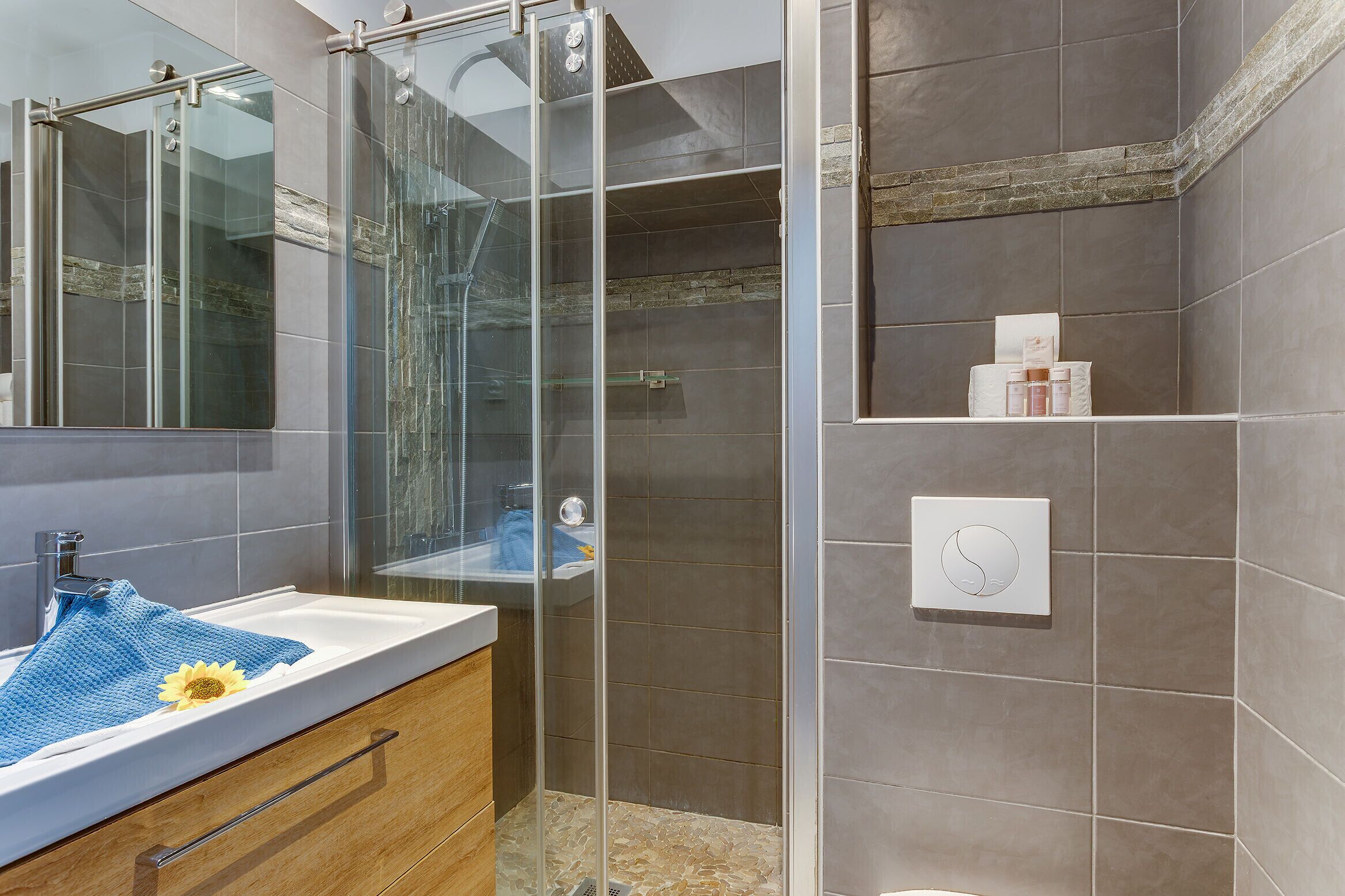 Un baño moderno con cabina de ducha de vidrio, un lavamanos con una toalla y un inodoro.