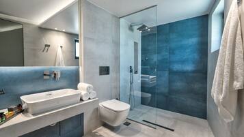 Un baño moderno con un lavamanos grande de color blanco, un inodoro y una ducha con mampara de vidrio.