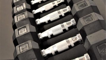 A row of dumbbells with weight markings, arranged on a flat surface.