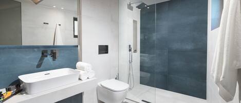 A modern bathroom with a large white sink, a toilet, and a glass-enclosed shower area.