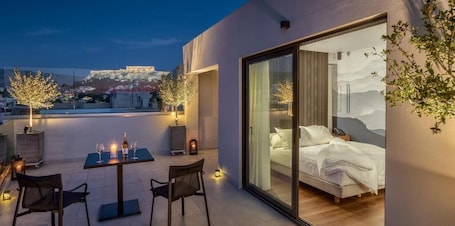 A modern hotel room with a balcony, a bed with white linens, and a view of a historic building in the background.