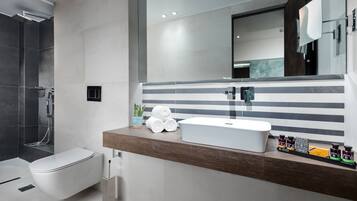 A modern bathroom with a white toilet, a large mirror, and a wooden vanity with a sink.