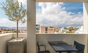 A balcony with a view of a cityscape, a potted tree, and a table with chairs. - Ivis 4 Boutique Hotel (Athens)