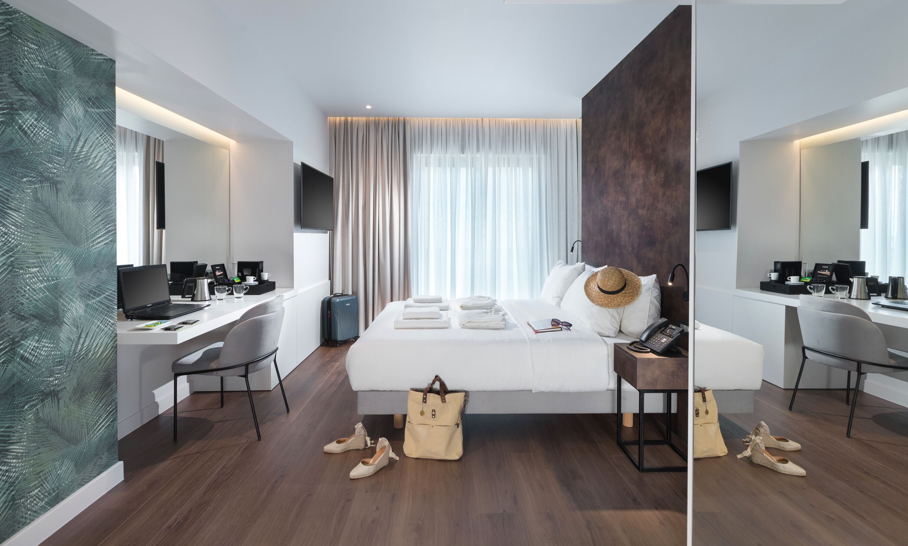 Ein modernes Hotelzimmer mit einem großen Bett, einem Schreibtisch, einem Stuhl, einem Koffer und einem Kleiderschrank.