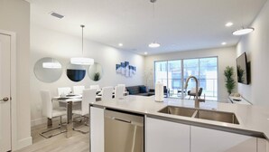 A modern kitchen with a dining area, large windows, and a view of the outdoors. - High luxury NEW 3 bedroom+loft townhouse in Hidden Forest, with private pool! (Clermont)
