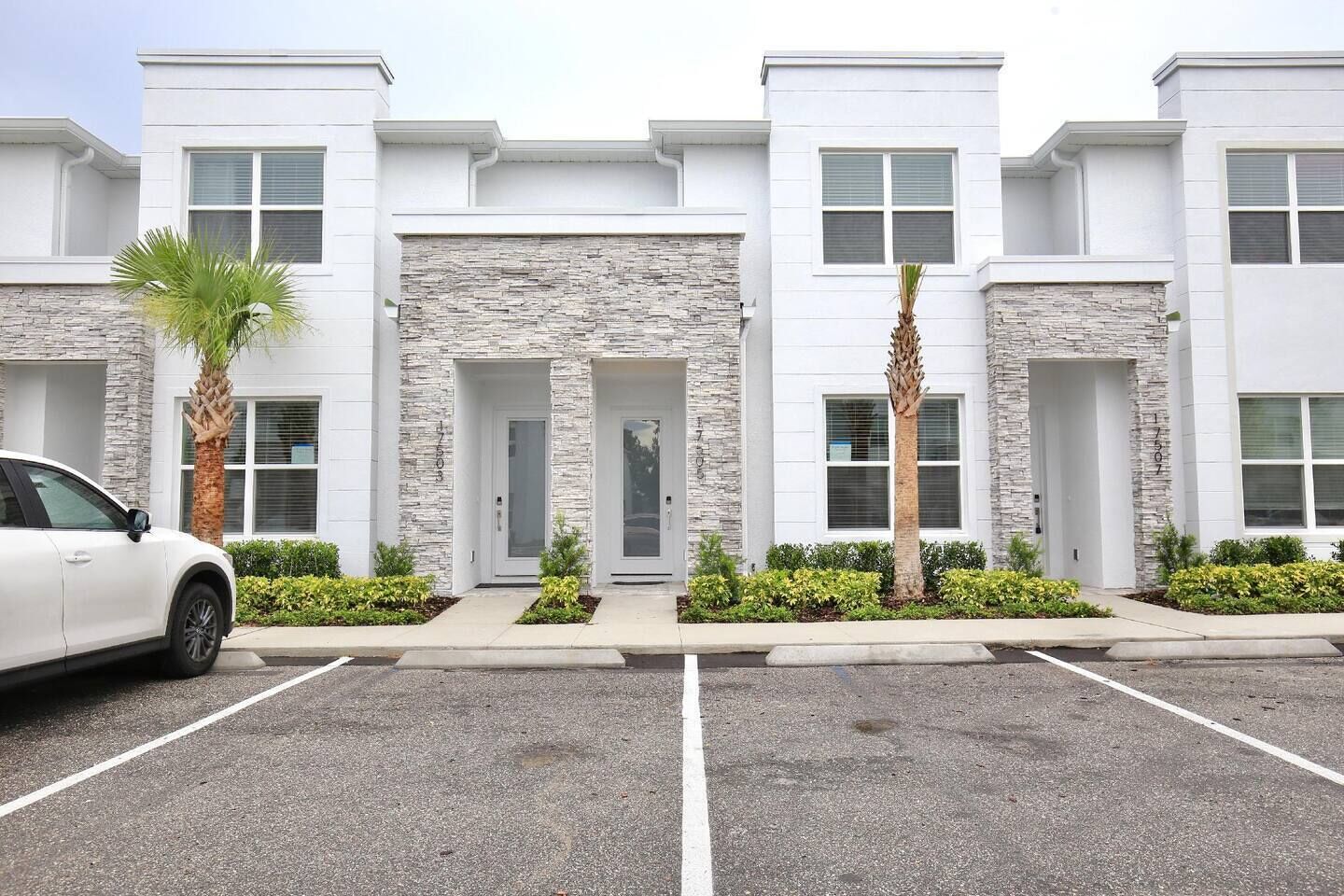 A modern building with a stone facade, multiple entry doors, and a parking lot.