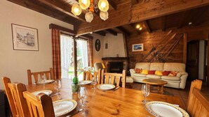 Ein Holzespeise-Tisch für vier Personen, mit Stühlen, einem Kamin, einer Couch und einer Treppe in einem rustikalen Ambiente.