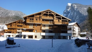 A multi-story wooden building with balconies, surrounded by snow and mountains.
