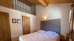 A bedroom with a bed, wooden door, and a staircase.