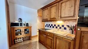 A kitchen with wooden cabinets, a tiled backsplash, and a countertop with a sink and various appliances.