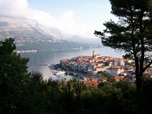 A coastal town with historic buildings, a marina, and a mountainous backdrop.