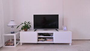 A white entertainment unit with a flat-screen TV, a lamp, and a potted plant. - A1 - Luxury apt in Center, Just 5min From Beach (Korcula)