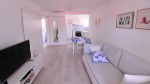 A modern living room with a flat-screen TV, a sofa with a floral pillow, and a dining area with a table and chairs. - A1 - Luxury apt in Center, Just 5min From Beach (Korcula)