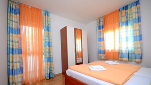 A bedroom with a wooden bed, orange bedding, and plaid curtains. - A2 - apt With 2 Balconies, 5 min Walking to Beach (Podstrana)