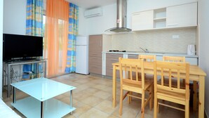 A compact kitchen with a dining area, a TV, and a small table. - A2 - apt With 2 Balconies, 5 min Walking to Beach (Podstrana)