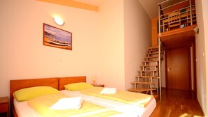 Une chambre d’hôtel avec deux lits, un tableau au mur et un escalier menant à un étage supérieur.