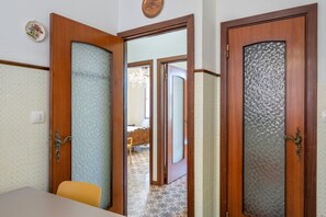 Um quarto com porta de madeira, uma mesa pequena e uma cadeira.