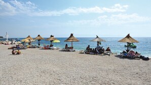 Una spiaggia con ombrelloni e lettini.