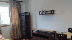 A compact living space with a sofa, a dining table with chairs, a small cabinet, and a window with curtains. - Villalomba (Villagarcía de Arosa)