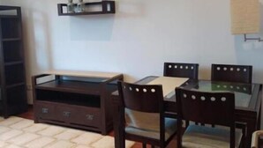 A dining area with a glass-top table, four wooden chairs, a dark wooden cabinet, and a small shelf with decorative items. - Villalomba (Villagarcía de Arosa)