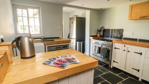 A kitchen with a wooden countertop, a kettle, a stove, and a refrigerator. - 54 Bridge Street (Brigg)