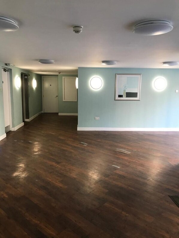 A spacious room with hardwood flooring, light blue walls, and recessed ceiling lights. - Apex Variety Gate Apartment (Glasgow)
