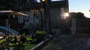 Un espace patio avec des sièges d’extérieur, une voiture et un bâtiment doté d’un toit en tuiles.