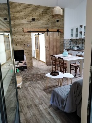 Un espacio habitable moderno con comedor, cocina y una puerta corrediza de vidrio que da a un área exterior.