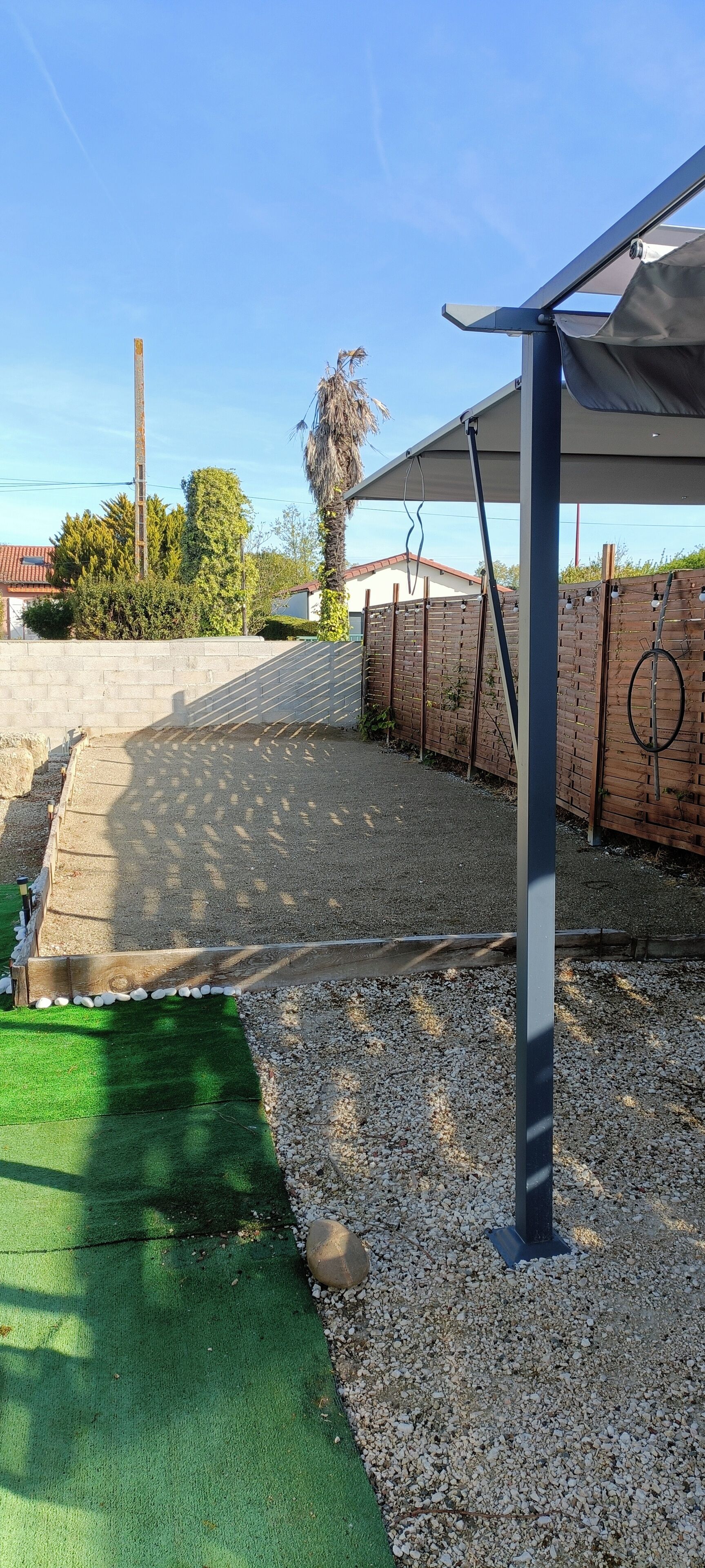 A covered outdoor area with a gravel path, artificial grass, and a brick wall.