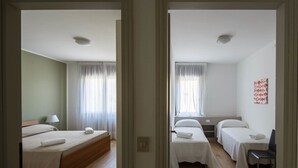 A hotel room with a bed, a bedside table, a chair, and a window with curtains.