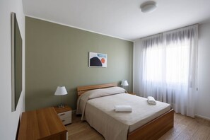 Una camera da letto con un letto, comodini, una lampada, un quadro e una finestra con tende.