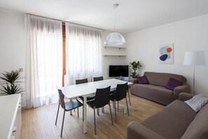 Un salon moderne comprenant un coin repas, un canapé, un téléviseur et une plante.