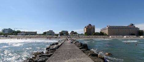 Un muelle que lleva a una playa con edificios al fondo.