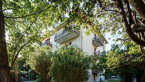 Un immeuble résidentiel à plusieurs étages, doté de balcons et entouré d’arbres et de verdure.
