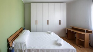 Une chambre d’hôtel avec un lit, un bureau et une armoire.