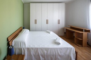 A hotel room with a bed, a desk, and a wardrobe.